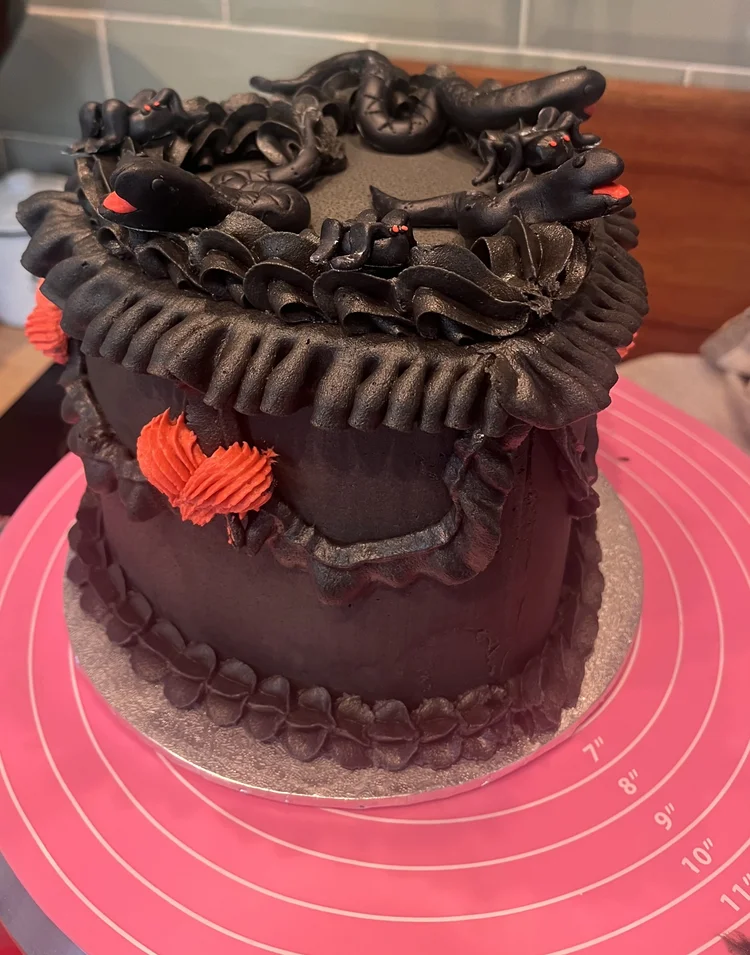 Black heart-shaped birthday cake with snake decorations