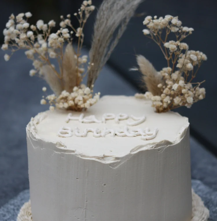 White birthday cake with dried flowers
