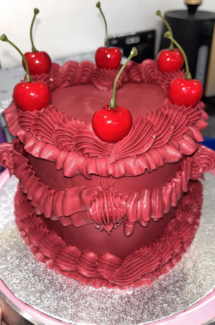Red heart-shaped birthday cake with cherries