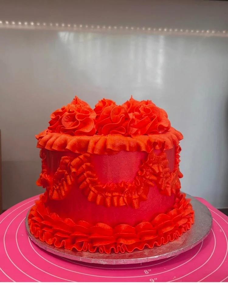 Red birthday cake with ruffled frosting and floral designs