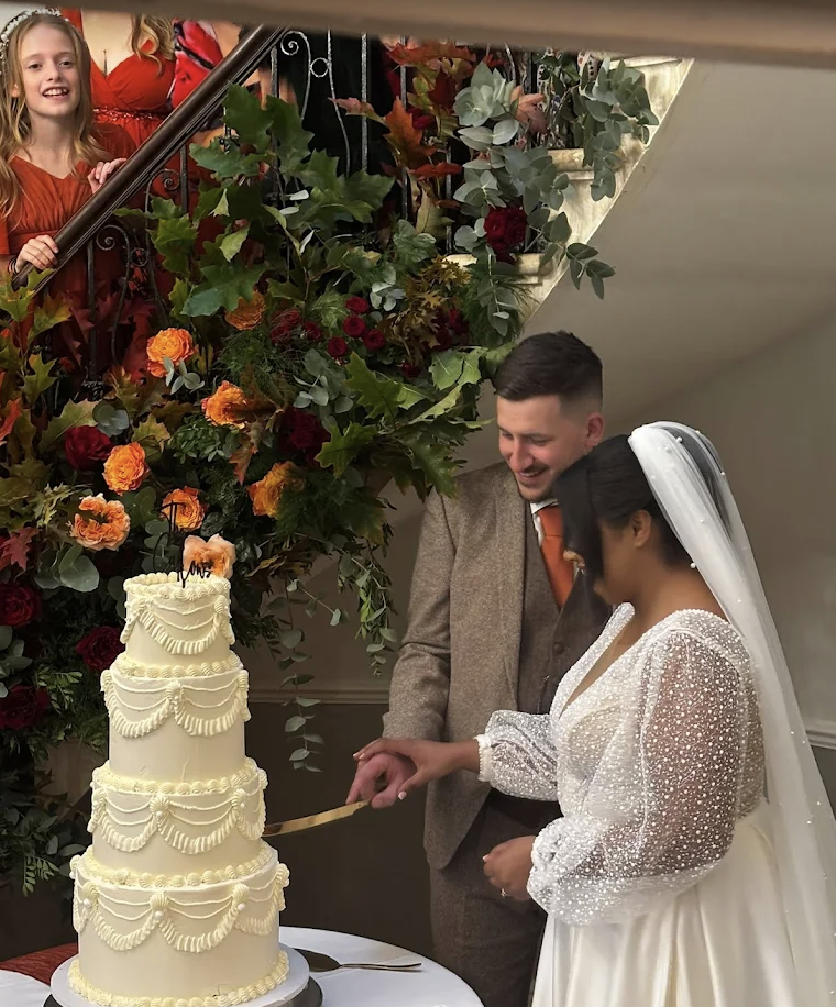 Bride and Groom cutting their four-tier white buttercream wedding cake