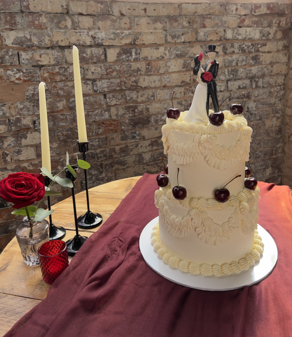 Gothic wedding cake with whiteout, black cherries, and skeleton topper